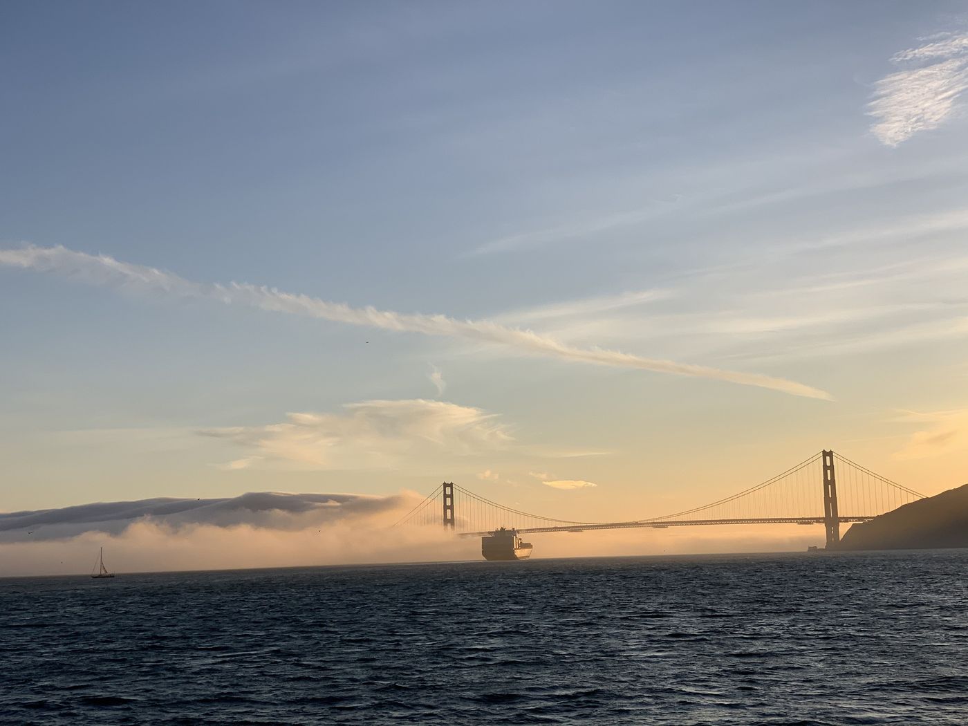 The Golden Gate Bridge at sunset, fog rolling in, seen across the water from Tiburon