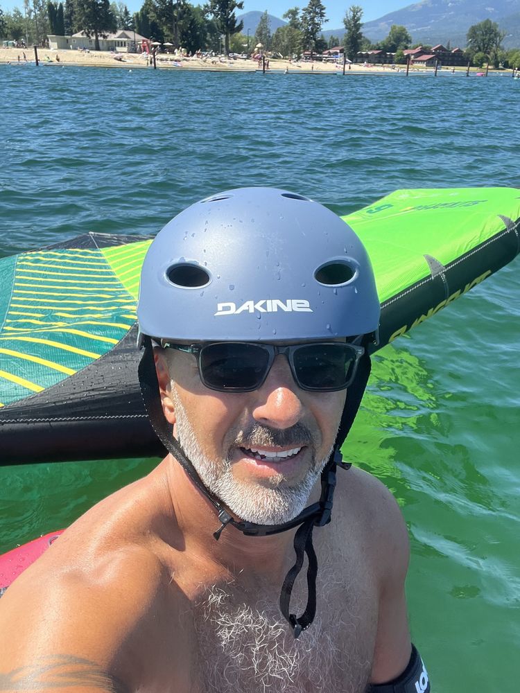 Chris in a helmet and sunglasses in the water with a wing-foil wing