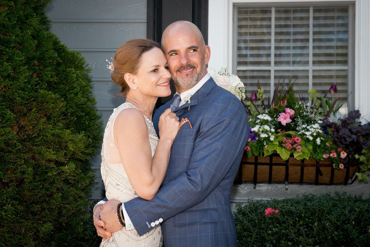 Chris and his wife embracing outside a house on their wedding day