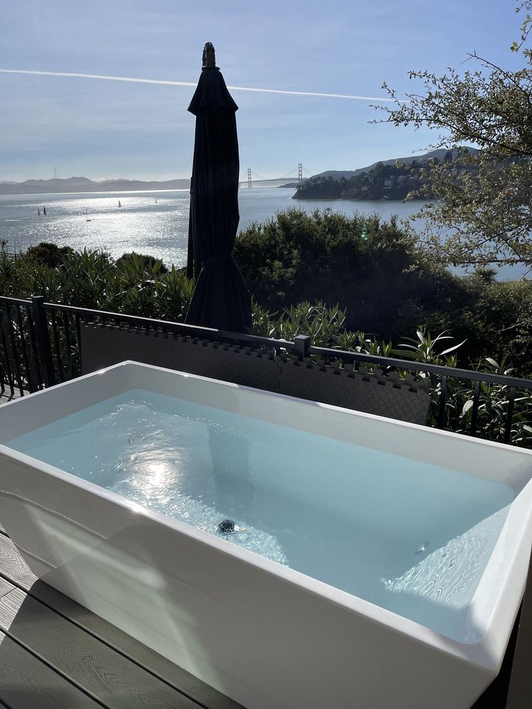 A cold-plunge tub on a deck overlooking the bay